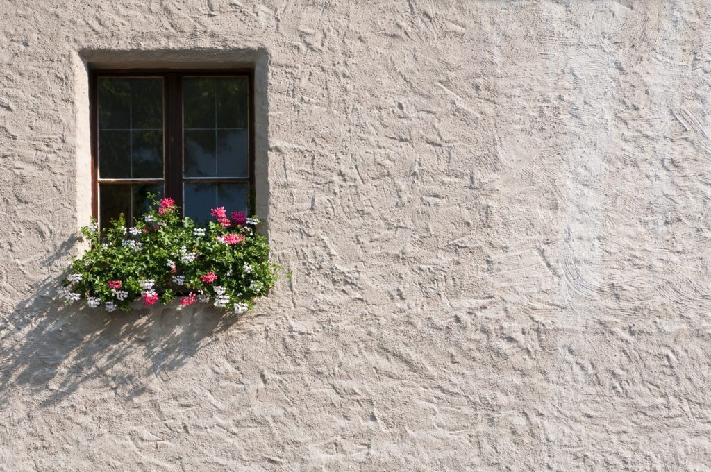 Potted plants outside a window of stucco building